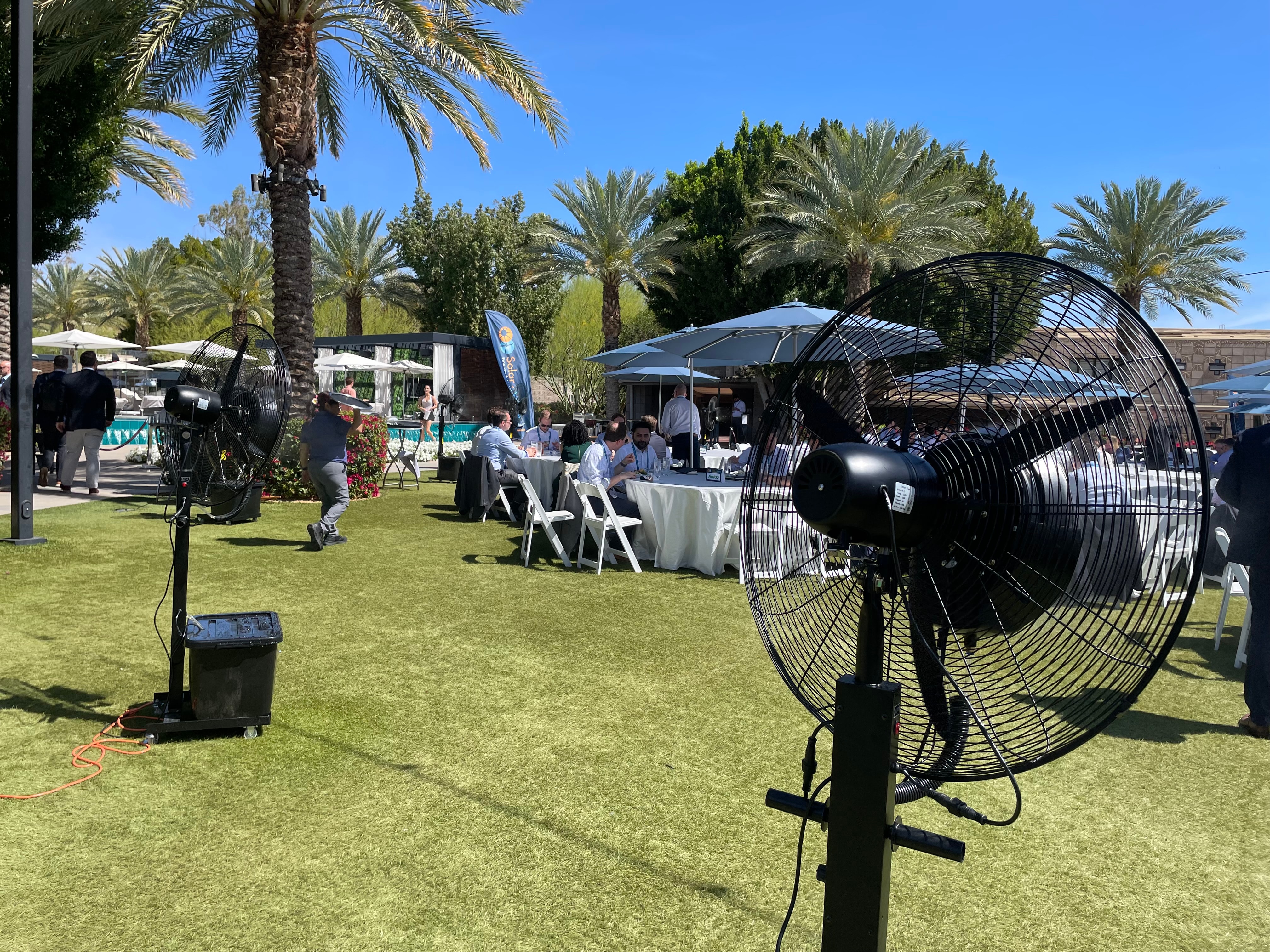 Misting fan near blue umbrella at event
